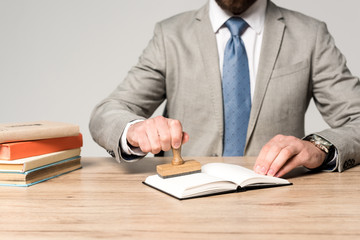 partial view of lawyer putting stamp in notebook isolated on grey