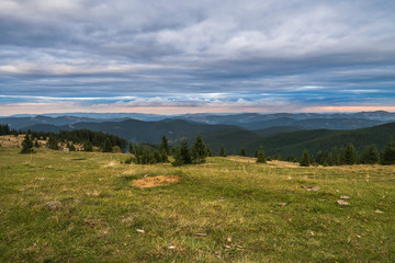 Summer landscape in mountains and the dark cloudy sky above.