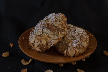 Traditional French croissant with almonds on the wood plate on dark background