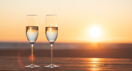 two glasses of champagne on the table at sunset