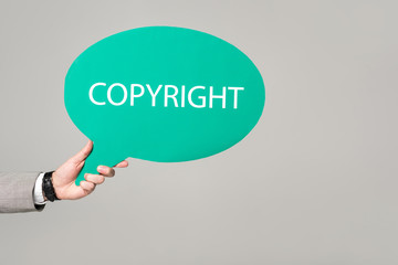cropped view of businessman holding thought bubble with copyright inscription isolated on grey
