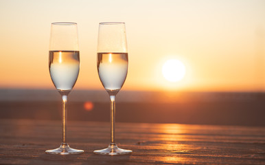 two glasses of champagne on the table at sunset