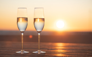 two glasses of champagne on the table at sunset