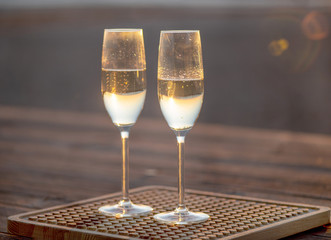 two glasses of champagne on the table at sunset