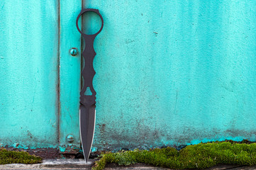 Military knife for attack and defense. Knife on a turquoise background.