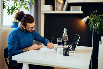 Creative caucasian bearded graphic designer sitting in his office and drawing in notebook.