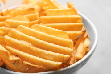 Bowl with tasty potato chips on table, closeup