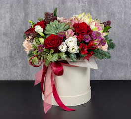 fresh arrangement of bright flowers in a hat box florist work place for text