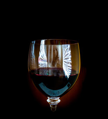 glass of thick red wine in a dark room with window reflections