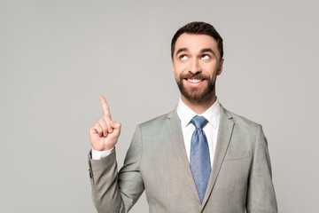 cheerful businessman looking away while showing idea gesture isolated on grey