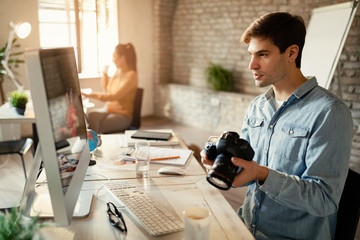 Young photographer using computer while working in the office.