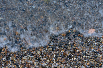 Shore with a rolling wave on small stones