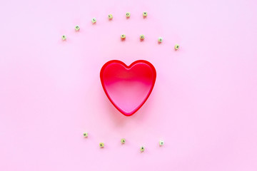 Creative holiday concept of love. Cookie cutter in a shape of heart on a pink background. Text Follow Your Heart made of wooden beads.  Valentine's Day concept. Top view, flat lay.