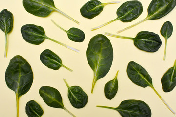 Pattern of fresh spinach leaves on yellow background. Top view.