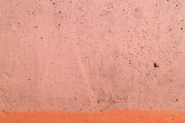 The pink concrete wall. The wall is textured.