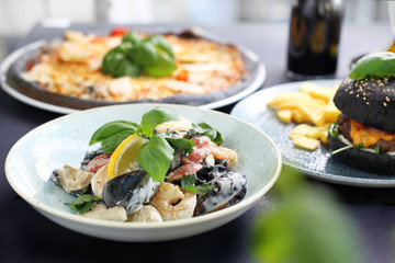 Black food. Burger, pizza, pasta, dishes with activated charcoal.