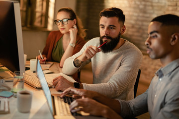 Young coworkers making business plans on laptop in the office.