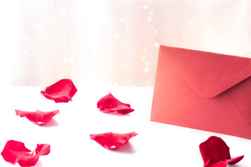 Red envelope with rose petals for Valentines Day, copy space for love letter text.