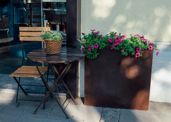 Traditional design chair and table next to pretty flowers at the door of a coffee shop.
