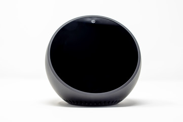 Round smart speaker with voice assistant integrated that also serves as a bedside clock.