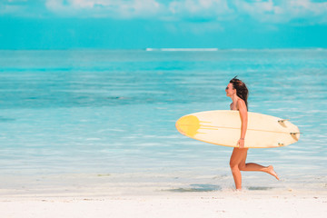 Naklejka na ściany i meble Beautiful surfer woman ready to surfing in turquoise sea, on stand up paddle board at exotic vacation