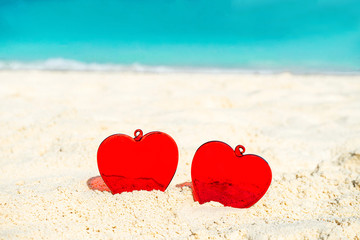 Fototapeta premium Red Heart shape on white yellow sand beach. Love concept for Valentine Day or summer vacation.