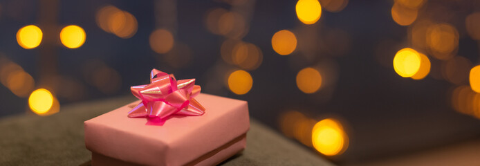 Pastel pink gift box with bow on background of defocused lights. Banner. St.Valentines day concept. Christmas concept. New Year concept.