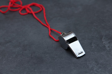 silberne Trillerpfeife liegt auf einer grauen Schiefertafel