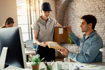 Young delivery woman giving package to a businessman who is working in the office.