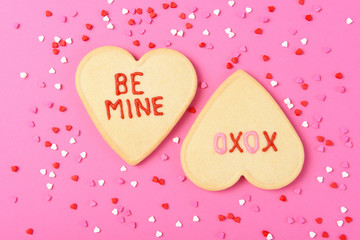 Valentines Day Concept: Two Heart shaped sugar cookies on pink  Be Mine and XOXO written in icing,...