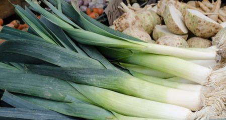 Stack of fresh leeks on a flea market counter. Fresh vegetables background.