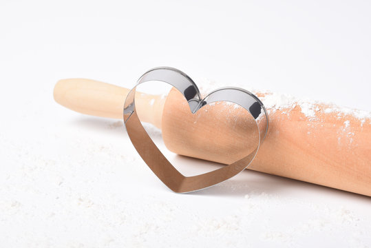 Valentines Day Concept: A heart shaped cookie cutter with flour and rolling pin on white with copy space,