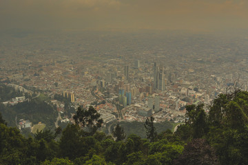Fototapeta premium Panorama photo of Colombia capital Bogota, viewed from a high perspective, looking towards the CBD on a hazy misty day. Misty cityscape.