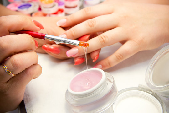 Master applies gel polish on nails in manicure salon