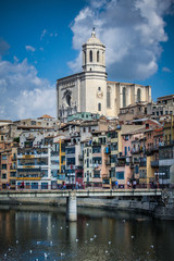 Fototapeta na wymiar Panorama of Girona from the river, with Girona cathedral of Saint Mary and a bridge seen in the foreground. Some clouds on the sky behind the church.