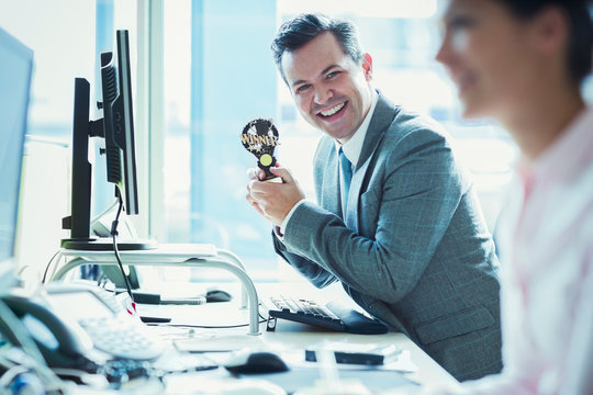 Portrait enthusiastic businessman holding winner trophy at desk in office