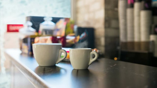 two cups of hot coffee on a bar counter behind frozen winter window 