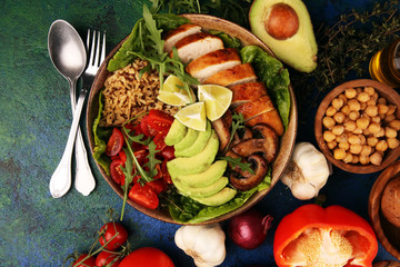 Healthy salad bowl with quinoa, tomatoes, chicken, avocado, lime and mixed greens and mushrooms