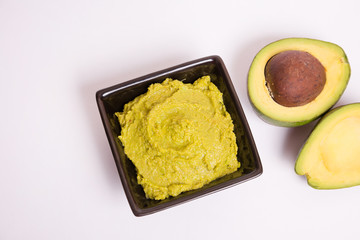 Guacamole con aguacates sobre fondo blanco.