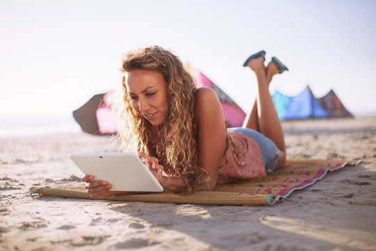 Woman Reading Digital Tablet On Beach Mat