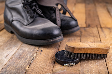 Polishing of military boots on a wooden table. Maintenance and protection of leather shoes.