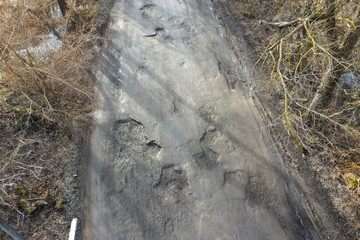 Large pits are filled with water on an asphalt road