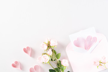 Pink paper hearts with gift box and roses on Light pink pastel paper background. Love and Valentine's day concept.