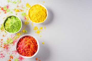 Holi festival celebration. Traditional Indian Holi colours powder decoration with paints. Top view of Organic Gulal colors in bowls on gray background for Holi festival.