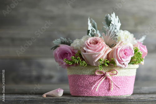Mothers Day flowers. Pink roses in basket on wooden background