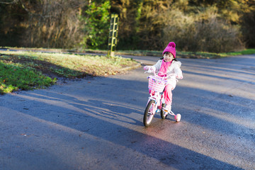 Obraz premium toddler girl ridding bicycle in winter countryside park, Northern Ireland