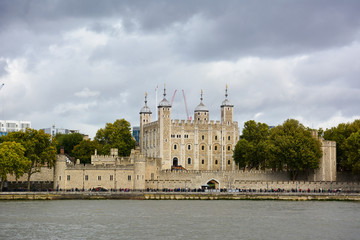 Tower of London, a castle and a former prison in London, England, seen from the River Thames on a cloudy day. Museum collections include famous British crown jewels