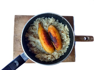 Fried bananas with rice on a pot with wooden board with white background. typical food of Guatemala