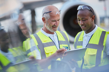 Air traffic control ground crew workers talking using digital tablet on airport tarmac