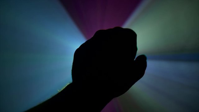 4K Shot Of Hand Reaching Out And Opening Hand Out Towards Beautiful Rays Of Light From Projector. Surrounded By Smoke. Multicoloured Light Moving Across. Dusk Flare On Camera Beautiful Colours